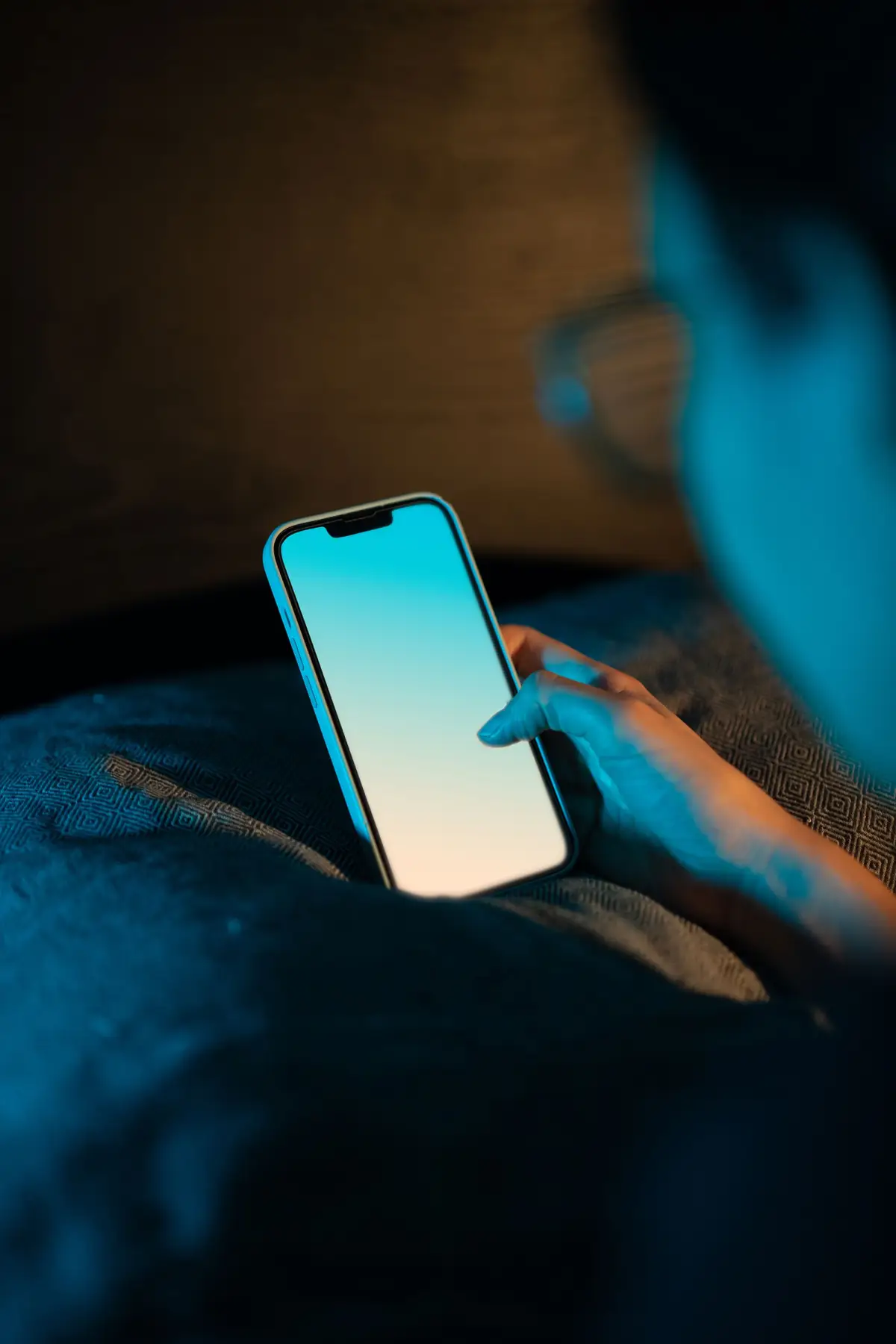 Hand holding a smartphone with a bright screen in a dimly lit room